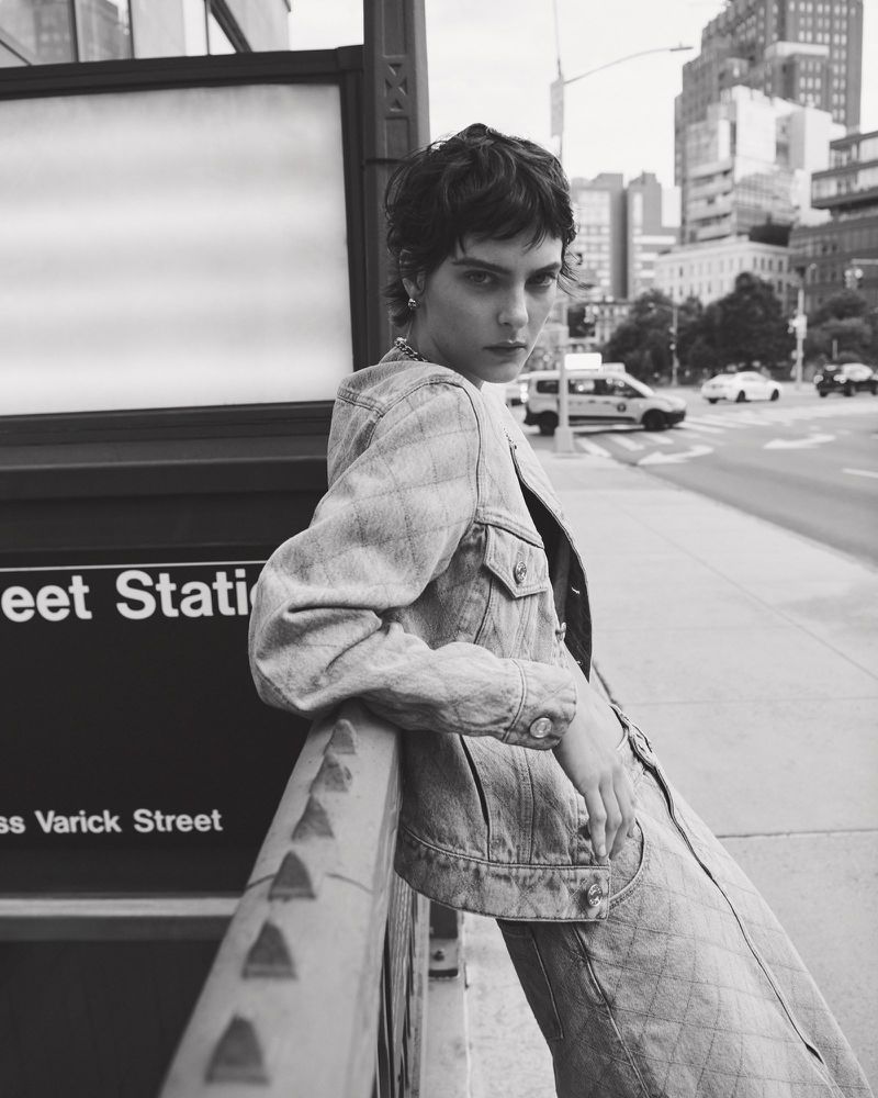 Model in quilted denim jacket leaning against a city subway station entrance in New York