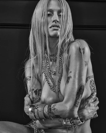 Black and white portrait of model Gabbriette posing with layered chain necklaces, bracelets, and numerous tattoos for CR Fashion Book.