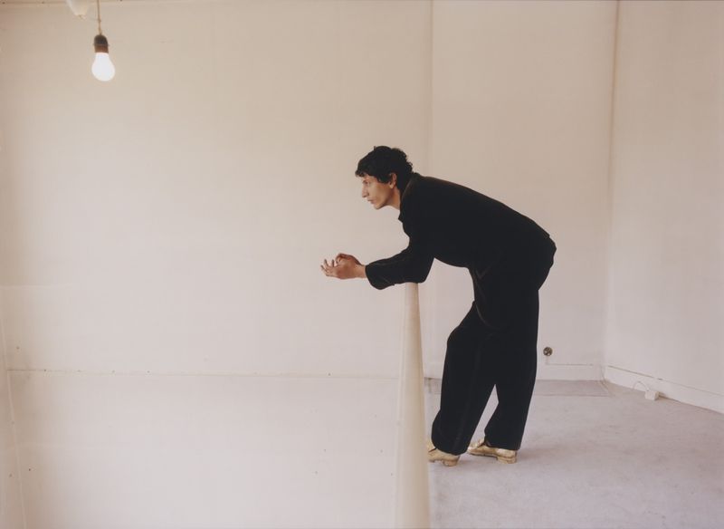 Takfarines Bengana leaning over a railing in a minimal white interior for The Menswear Edit