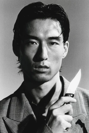 Close-up portrait of a man holding a knife, wearing a plaid blazer, shot in monochrome for HERO Magazine.
