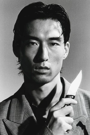 Close-up portrait of a man holding a knife, wearing a plaid blazer, shot in monochrome for HERO Magazine.