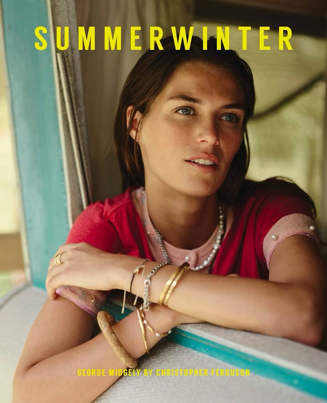 Portrait of a brunette woman with jewelry near a window wearing a pink cardigan, GEORGE MIDGELY BY CHRISTOPHER FERGUSON.