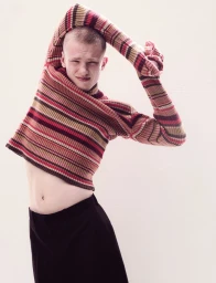 Model Joel Kemp wearing a striped turtleneck sweater and black trousers against a plain white background