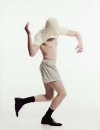 Model with t-shirt pulled over head wearing striped shorts and black dress shoes against white background