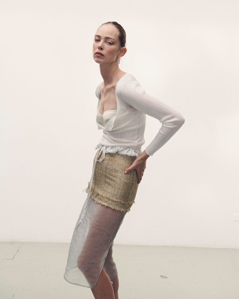 Model wearing a white top and textured skirt against a plain studio background for Des Phemmes spring/summer 2027.