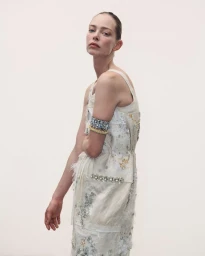 Model wearing embellished white dress with arm cuff against white background for Des Phemmes Spring/Summer 2027.