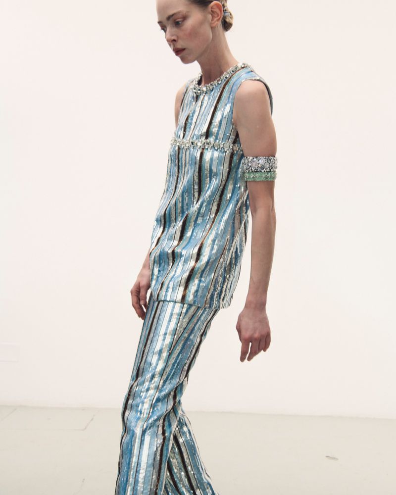 Model wearing a metallic blue striped top and matching trousers against a white seamless background
