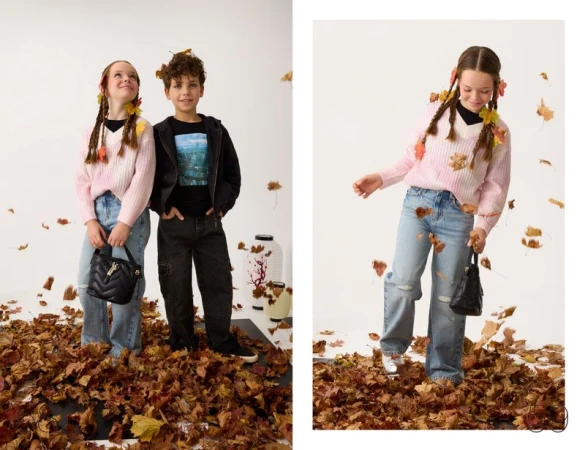 Two young models posing amidst falling autumn leaves on a white background for Guess Kids