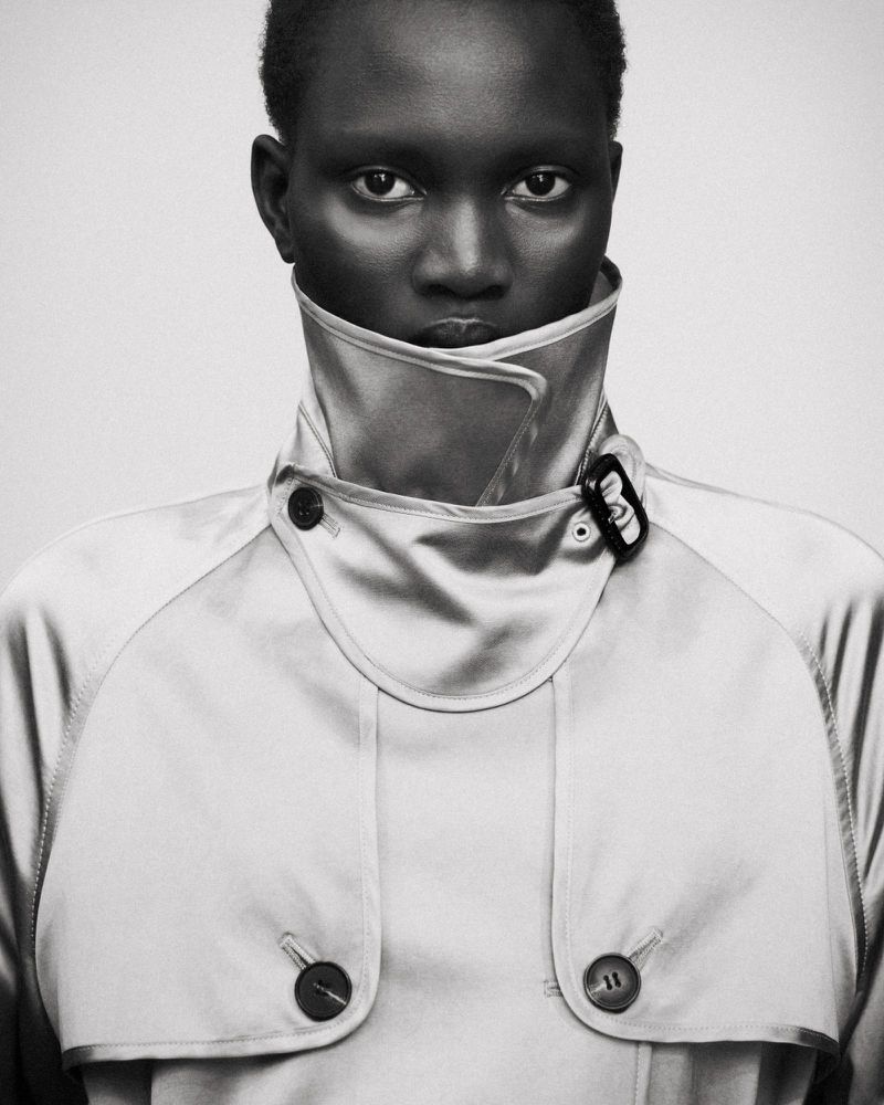Portrait of a model wearing a high-collared trench coat against a plain light background