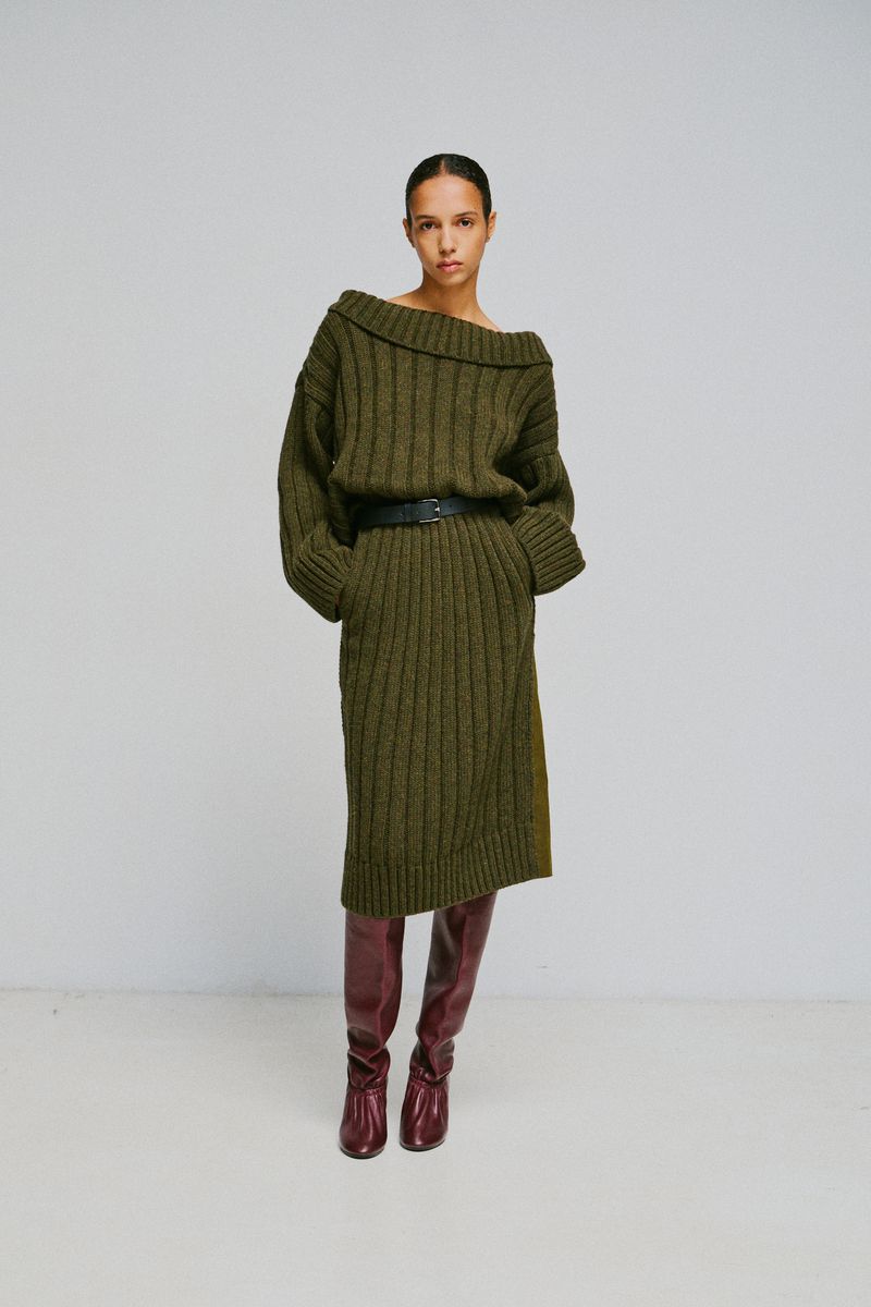 Model wearing an olive green ribbed knit dress and tall burgundy leather boots against a white background