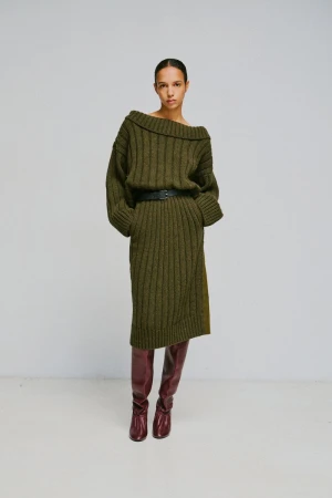 Model wearing an olive green ribbed knit dress and tall burgundy leather boots against a white background