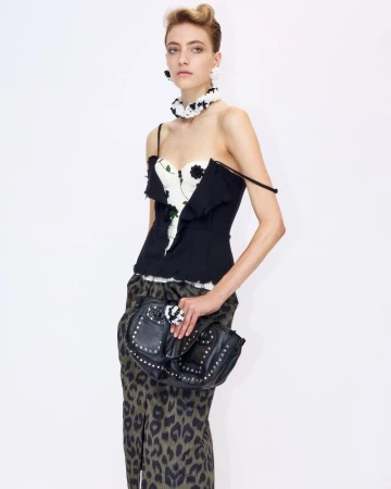Model wearing a black and white floral top, leopard print skirt, and studded black handbag against a white background