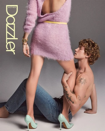 Woman in fuzzy pink dress and blue jeans with a seated shirtless tattooed man in a fashion editorial for Mother The Dazzler.