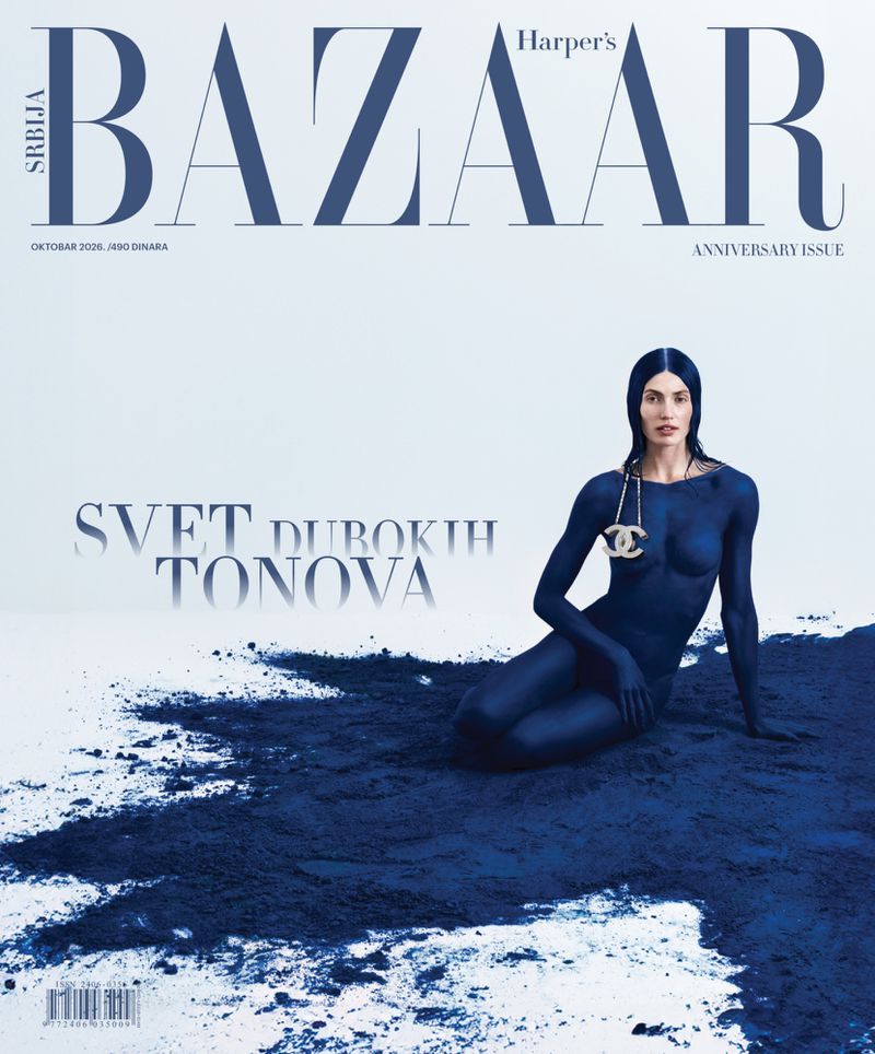 Seated woman with blue body paint wearing a gold necklace against a white background for a magazine cover