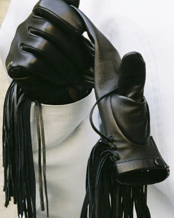 Close-up of black leather gloves with fringe details against a white background for Carven FW26/27.