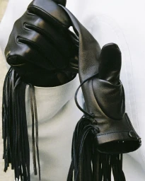 Close-up of black leather gloves with fringe details against a white background for Carven FW26/27.