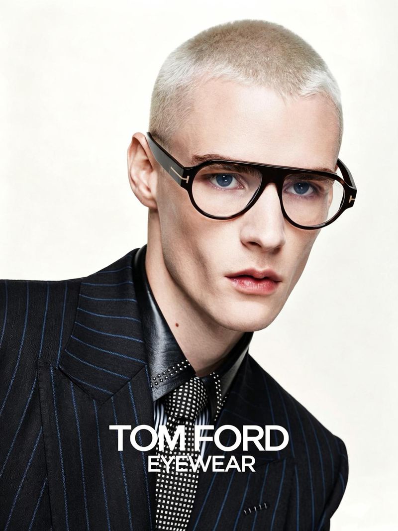 Model with bleach blonde buzzcut wearing black eyeglasses and a pinstripe suit for Tom Ford eyewear campaign.