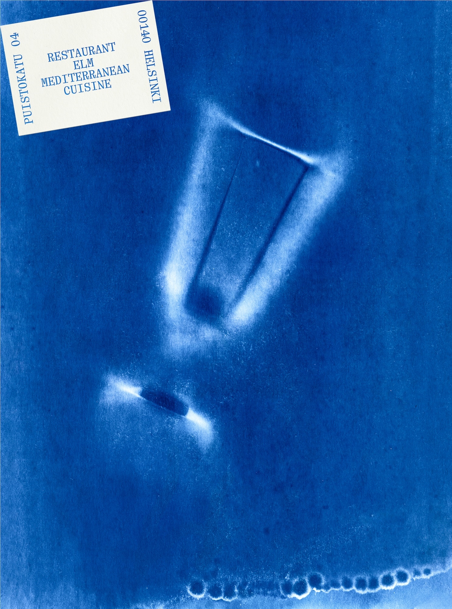 Cyanotype print in deep blue featuring a glowing silhouette of a wine glass and a white label with blue text in the corner
