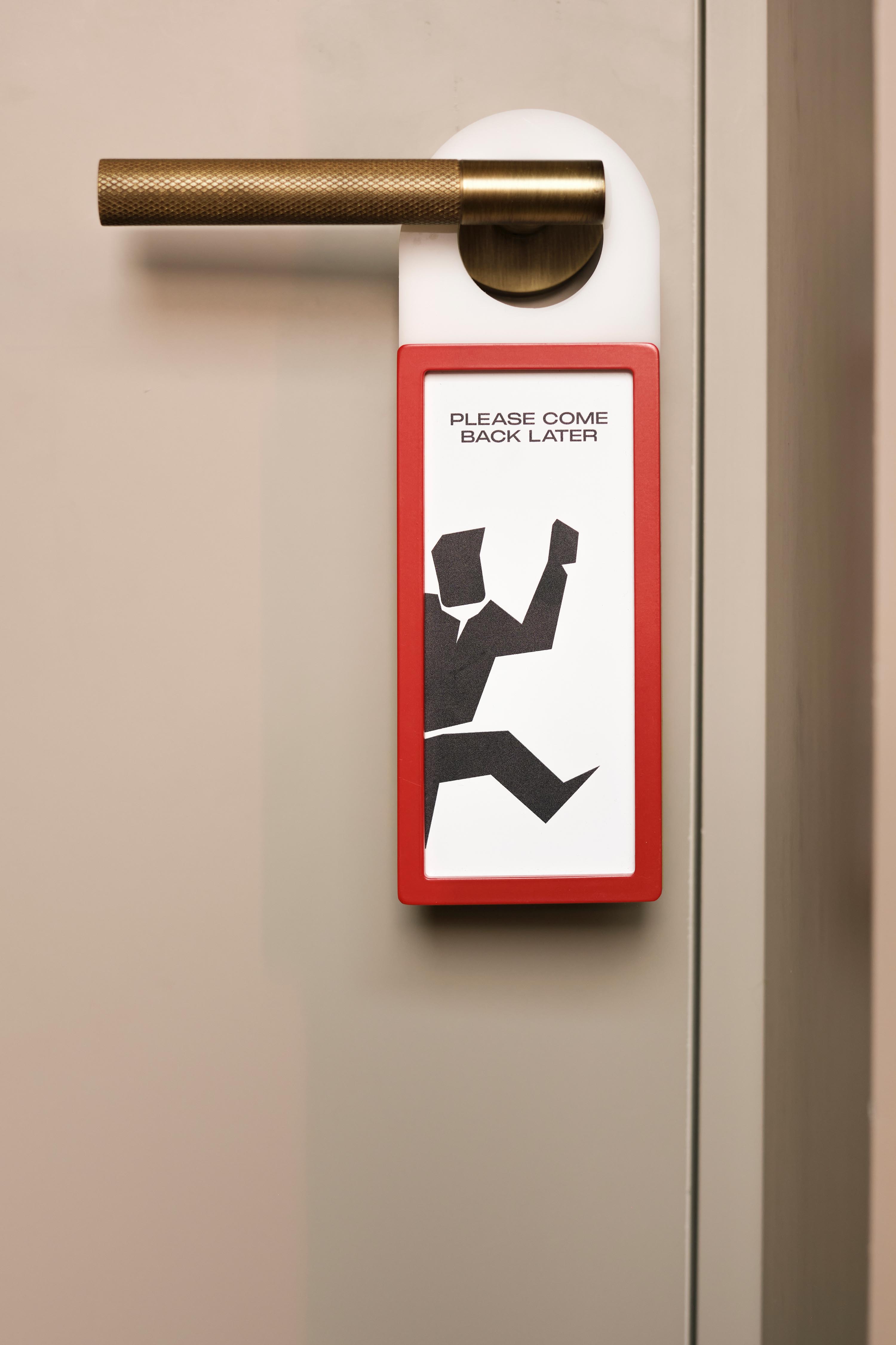 Custom door sign reading Please Come Back Later hanging on a metallic handle