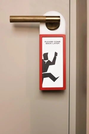 Custom door sign reading Please Come Back Later hanging on a metallic handle