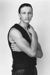 Monochrome portrait of a male model wearing a dark sleeveless top against a plain light background.