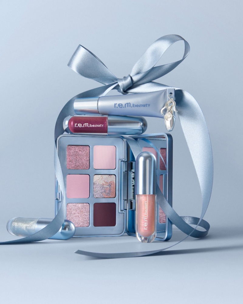 r.e.m. beauty makeup products tied with a silver ribbon against a light blue studio background