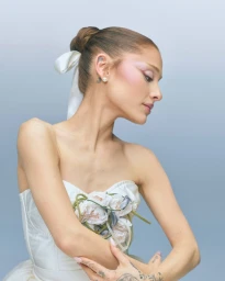 Ariana Grande in a white dress with floral details and a bow in her hair for r.e.m. beauty En Pointe Holiday 2026.