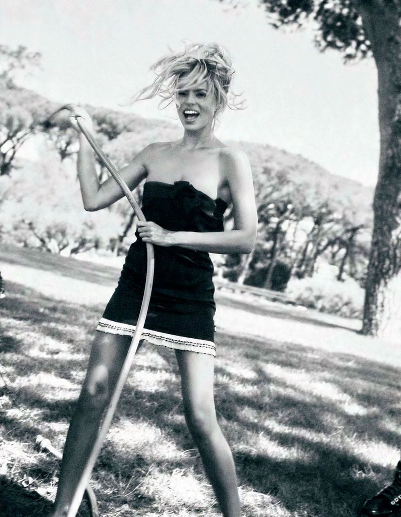 Model Brooks Nader in a black strapless dress holding a garden hose in an outdoor park setting for Von Magazine.