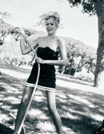 Model Brooks Nader in a black strapless dress holding a garden hose in an outdoor park setting for Von Magazine.