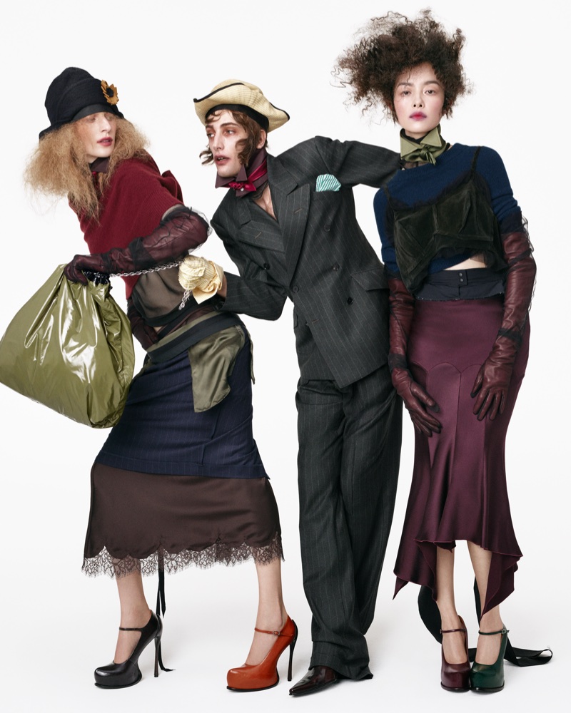 Three fashion models posing against a white studio background wearing layered designer outfits and heeled shoes.