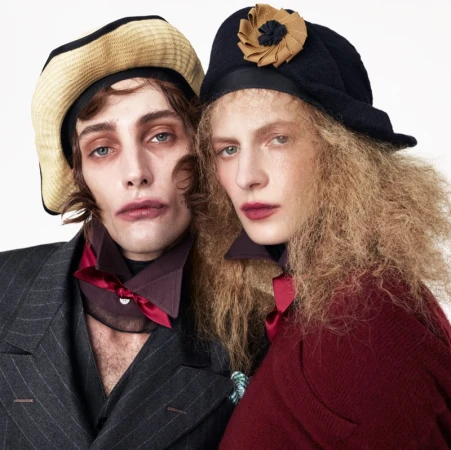 Two models posing closely in Zara Re{form} campaign wearing tailored jackets, patterned hats, and neck scarves against white.
