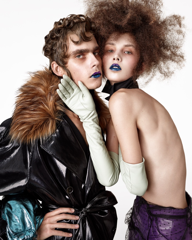 Close-up portrait of two models wearing blue lipstick and high fashion clothing against a white background