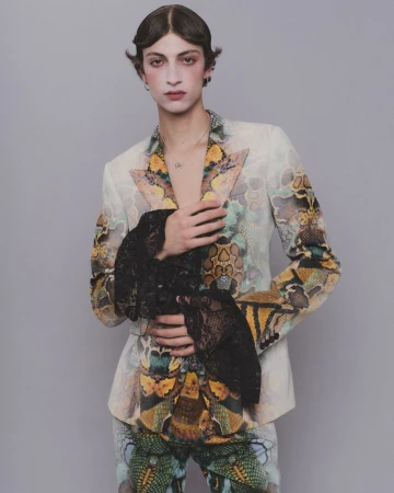 Model wearing a patterned jacket with black lace cuffs against a grey background for HERO Magazine.