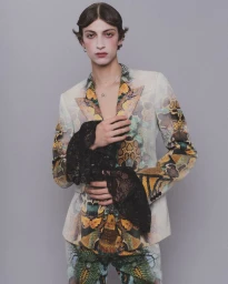 Model wearing a patterned jacket with black lace cuffs against a grey background for HERO Magazine.