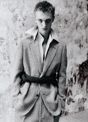 Monochrome portrait of a young male model in a patterned blazer and white shirt against a textured background