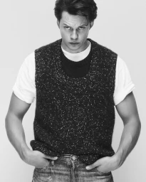 Portrait of Bill Skarsgård wearing a dark knitted vest over a white t-shirt for Fantastic Man