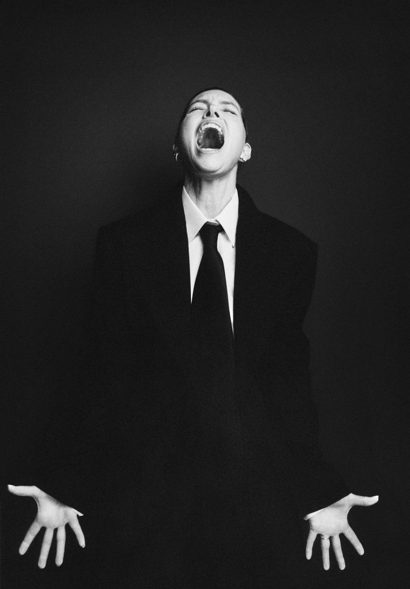 Jessica Biel in a black suit and tie with mouth open against a dark background for M Revista de Milenio