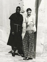 Two male models posing outdoors against a textured stone wall in black and white fashion editorial photography