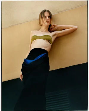 Model leaning against a wall wearing an olive green bandeau top and a long black skirt for WRPD Magazine.