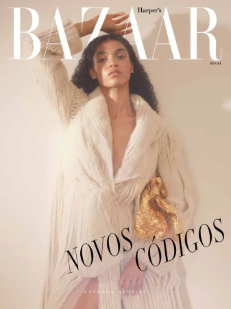 Raynara Negrine in a white cable-knit cardigan and gold handbag against a neutral background for Harper's Bazaar Brazil August 2026 cover.