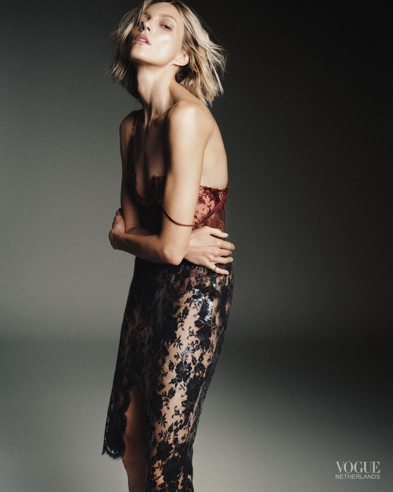 Model Anja Rubik wearing a patterned lace dress against a dark grey studio background for Vogue Netherlands October 2026 cover