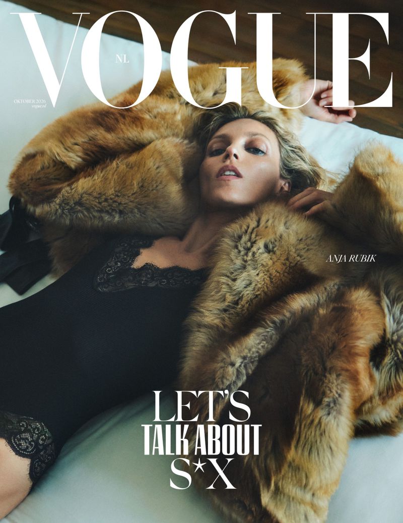 Model Anja Rubik lying on a white bed wearing a black lace bodysuit and a fluffy brown fur coat for Vogue Netherlands