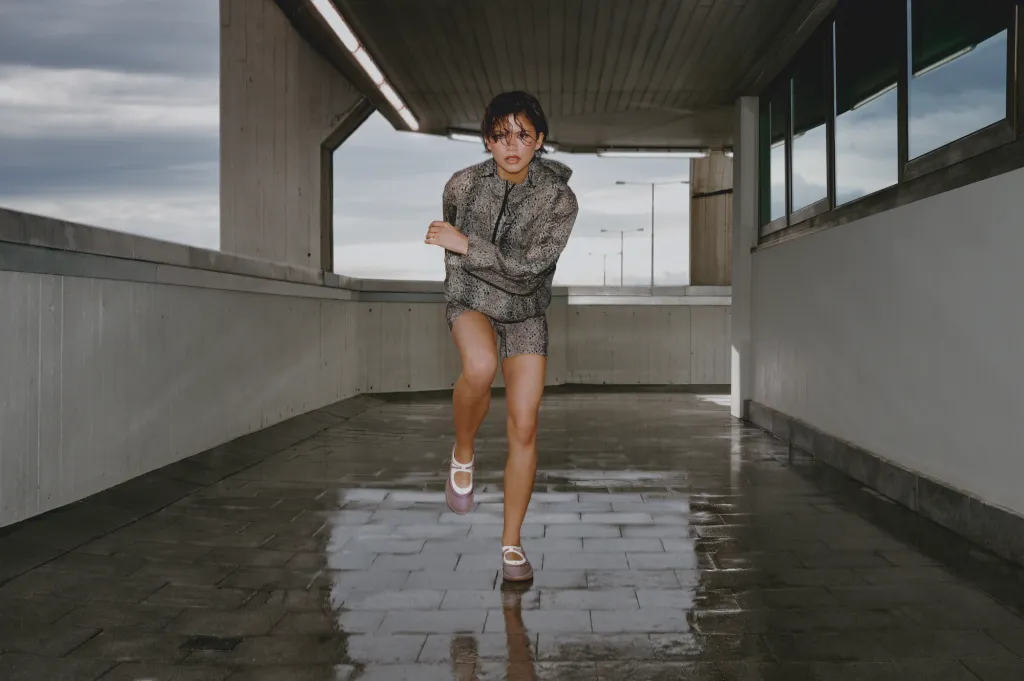 Zendaya running on a concrete walkway wearing patterned athletic wear and white shoes in an On campaign directed by Spike Jonze.