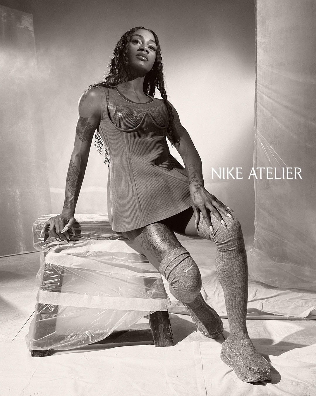 Sha'Carri Richardson in a fitted athletic top and high socks posing on a wrapped stool for Nike Atelier
