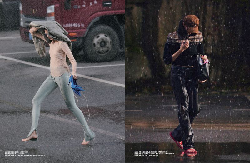 Two fashion models walking through heavy rain on a wet asphalt street near a large red truck.