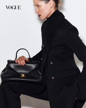 Model Hana Jirickova in a black blazer holding a black leather handbag against a plain white background for Vogue Thailand