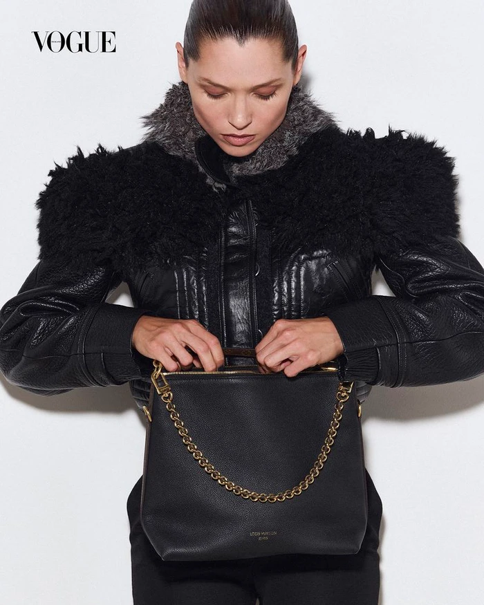 Model Hana Jirickova holding a black handbag wearing a black leather jacket with faux fur collar