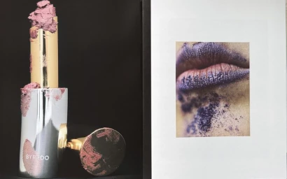 Smudged metallic lipstick tube next to a printed photo showing textured purple lips.