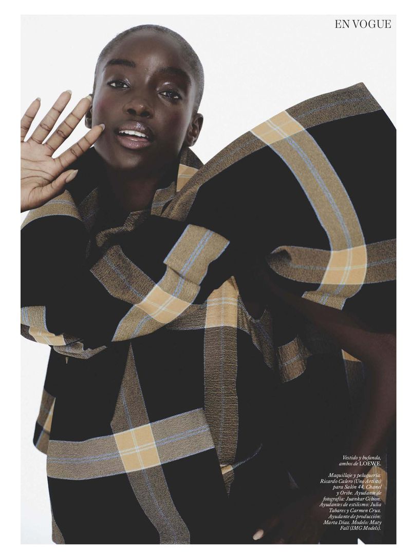 Model Maty Fall wearing a black and beige plaid coat raising her hand in an editorial for Vogue Espana