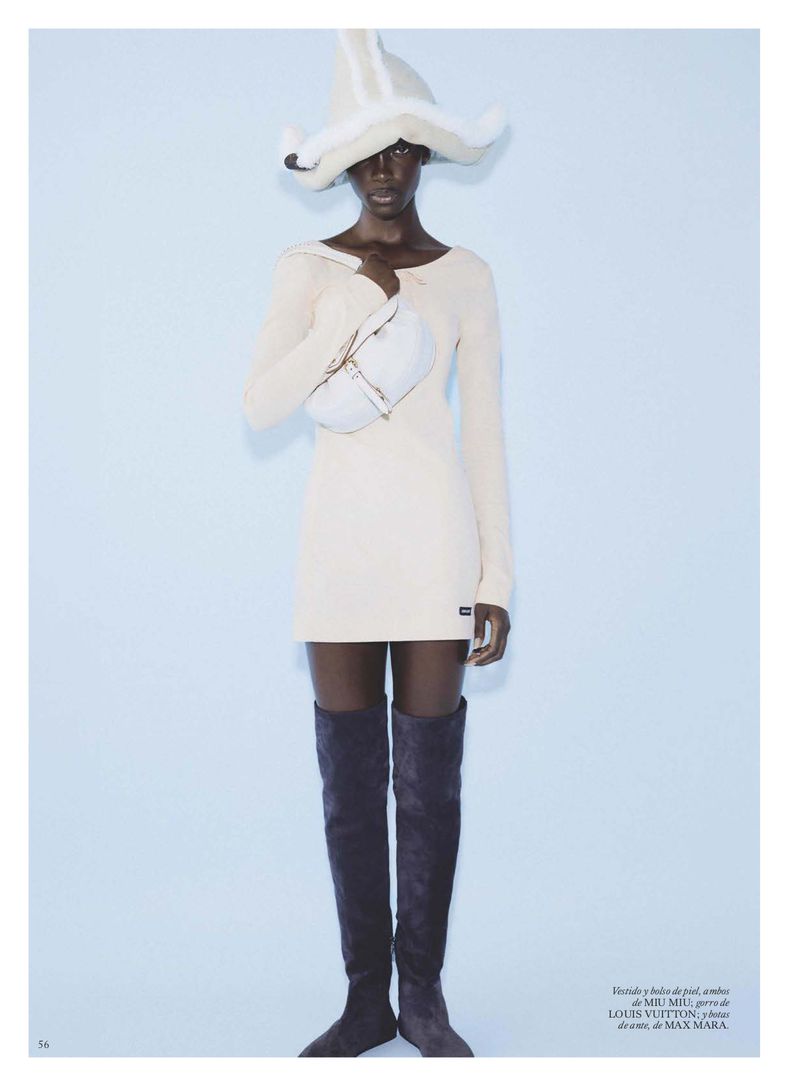 Model Maty Fall wearing cream dress, thigh-high boots, and sculptural hat holding a bag for Vogue Espana